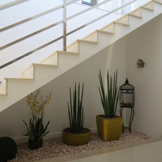 Des vases placés sous les escaliers créent un espace vert dans la maison.