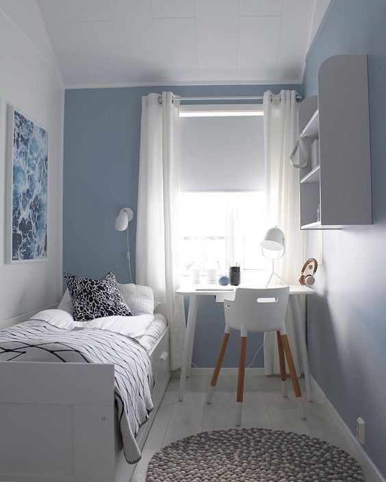 Chambre simple au décor blanc et bleu.