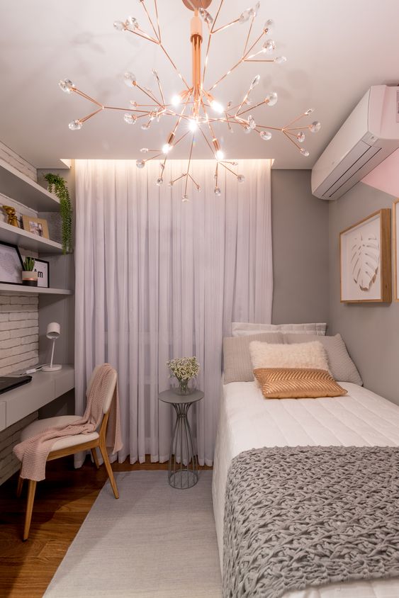 Chambre simple avec grand lustre et petites fleurs en pot.