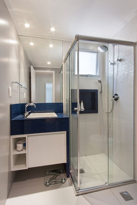 Salle de bain blanche avec lavabo bleu et alcôve.