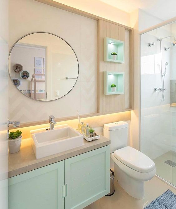 Petit décor de salle de bain avec des miroirs ronds et des alcôves éclairées avec de petites plantes en pot. 