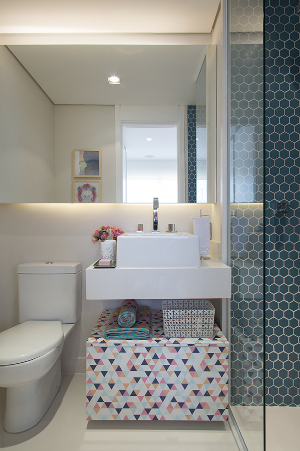 Petit décor d'appartement avec valises colorées dans la salle de bain et revêtement bleu à l'intérieur du caisson.
