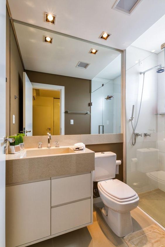 La salle de bain est décorée de grands miroirs et de lumières LED intégrées au plafond. 