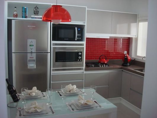 Cuisine en L avec inserts rouges.