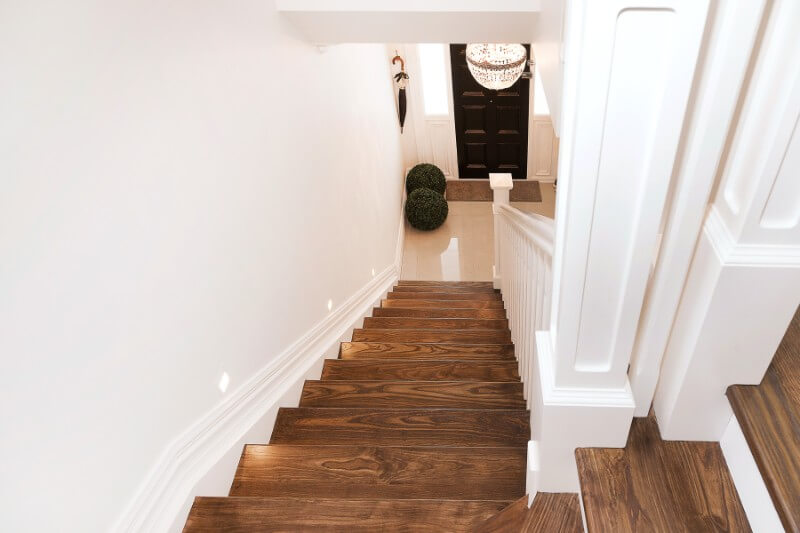 Escalier en bois avec main courante blanche.