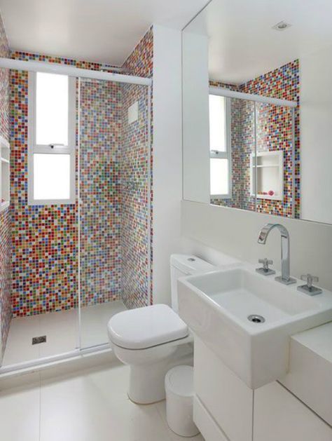 Salle de bain avec plan blanc, mur de douche avec carreaux de couleur rouge à prédominance. 