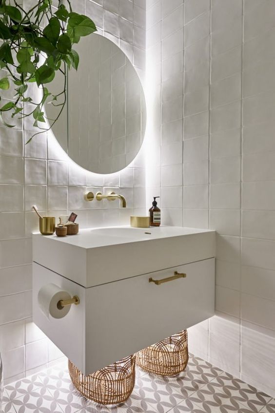 Salle de bain plan blanc avec métal doré et éclairage derrière le miroir.