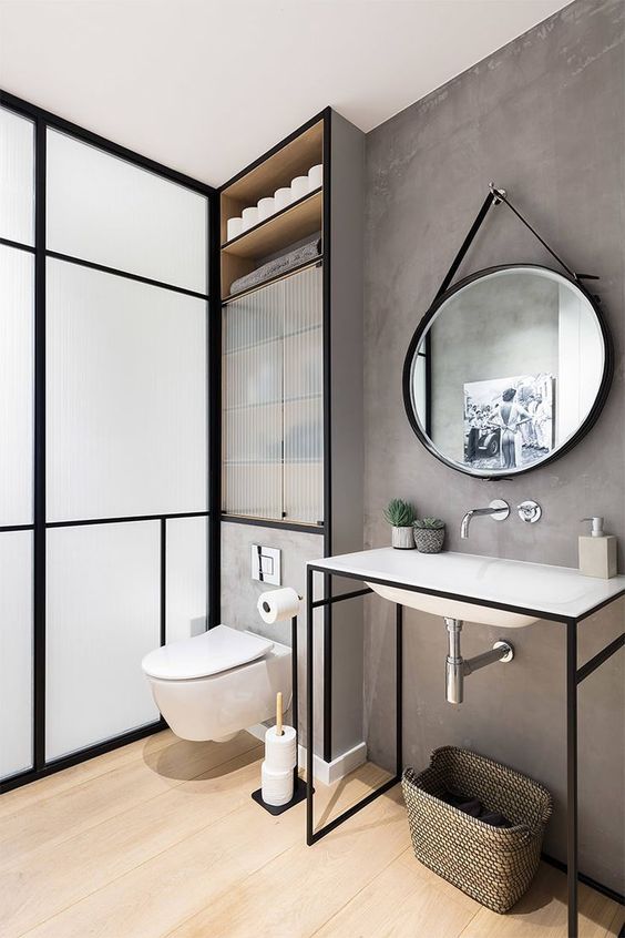 Les murs gris et les miroirs ovales laissent un cadre moderne et industriel dans la salle de bain prévue.