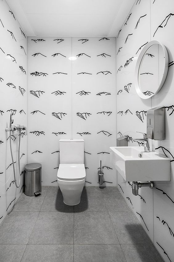 Salle de bain blanche avec des dessins au trait noir sur les murs.