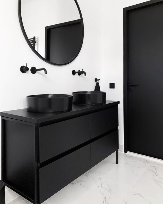 Salle de bain minimaliste avec finition blanche et robinets, éviers, armoires et portes noirs.
