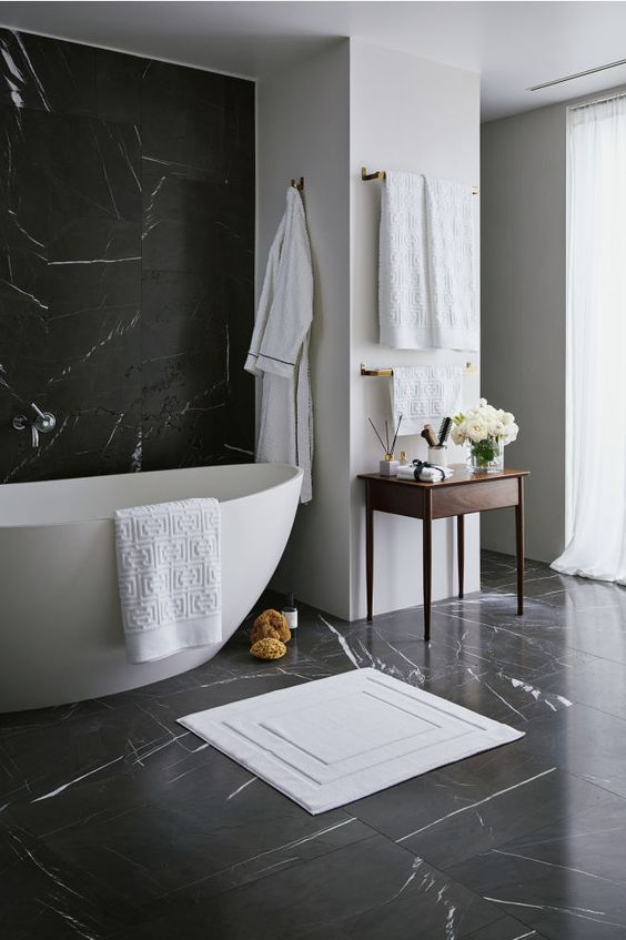 Salle de bain noire et blanche décorée de serviettes et de tapis.