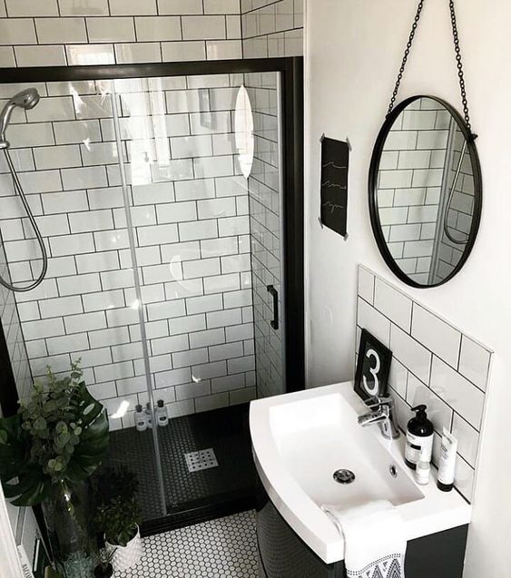 Salle de bain blanche avec des détails noirs sur les miroirs, les boîtes et les peintures.