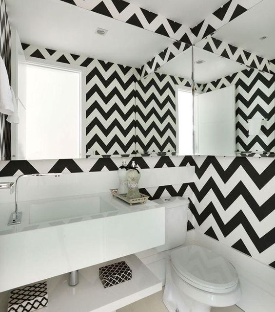 Salle de bain avec murs en miroir et revêtement de couleur diffuse.