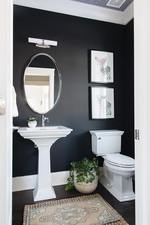 Salle de bain aux murs et sols noirs et lavabo avec toilettes blanches.