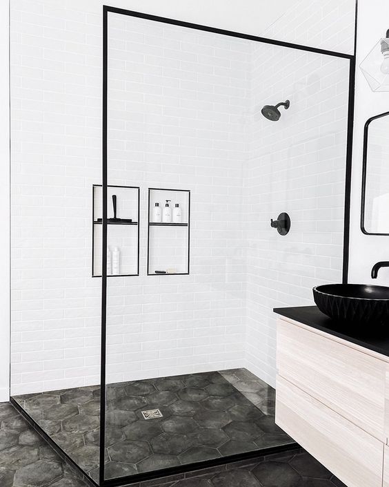 Salle de bain blanche avec détails noirs et sol en ciment.