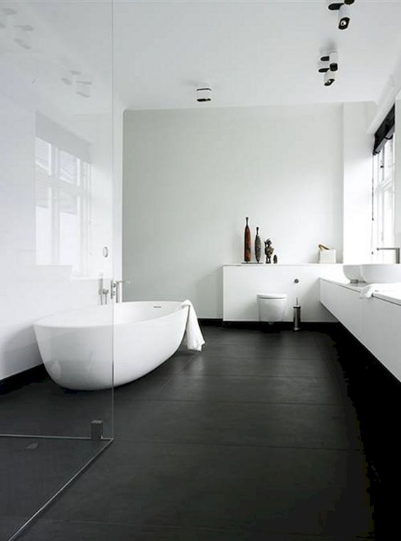 Grande salle de bain avec baignoire, deux lavabos et sols noirs.