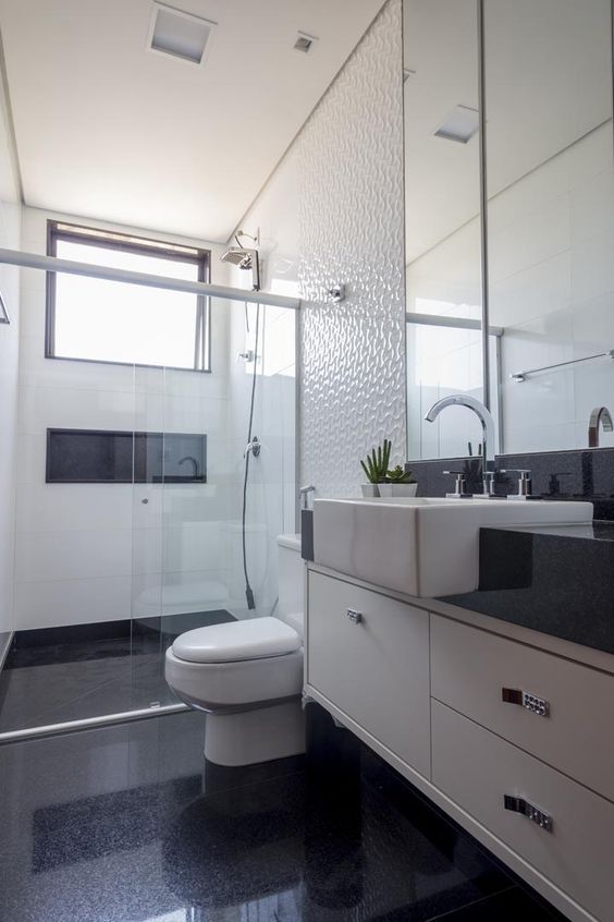 Salle de bain avec sol noir et murs texturés blancs.