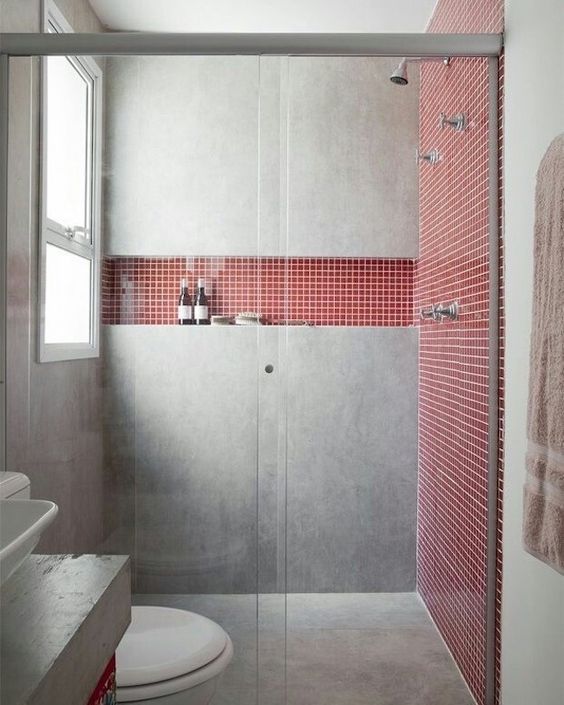 Salle de bain gris ciment avec murs en carrelage rouge.