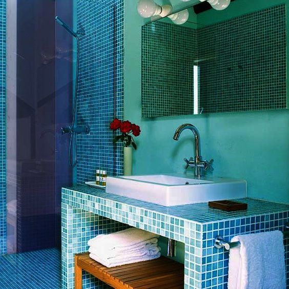 La salle de bain bleue et verte est décorée de vases dans le lavabo.