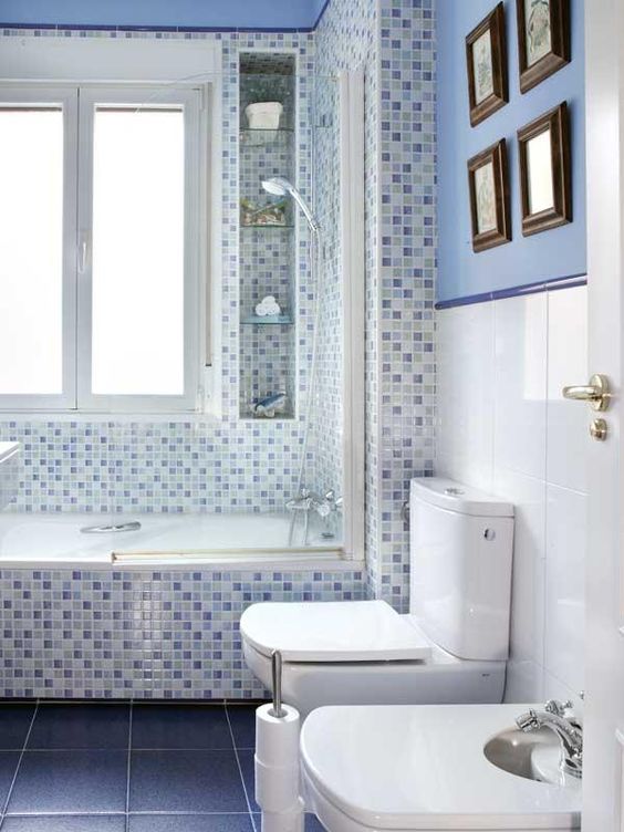 Les murs de la salle de bain sont divisés en blanc et bleu et sont décorés de peintures.