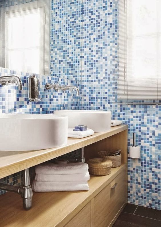 La salle de bain a des armoires en bois, un lavabo blanc et des murs carrelés bleus.
