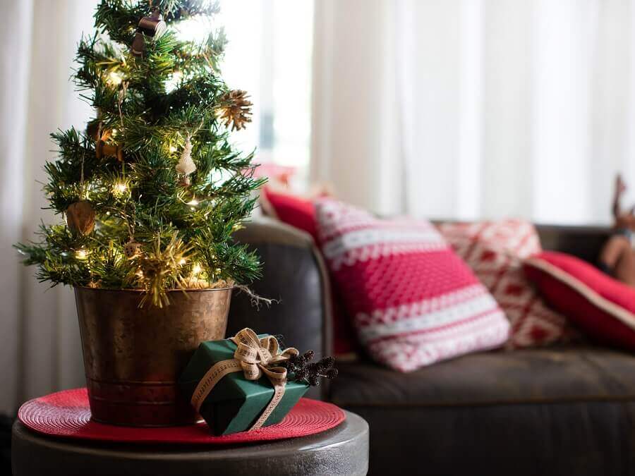 Décoration de Noël pour une petite chambre avec sapin et coussins thématiques.