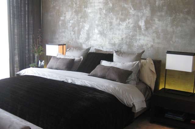 Chambre moderne avec des murs en ciment brûlé et un décor luxueux.