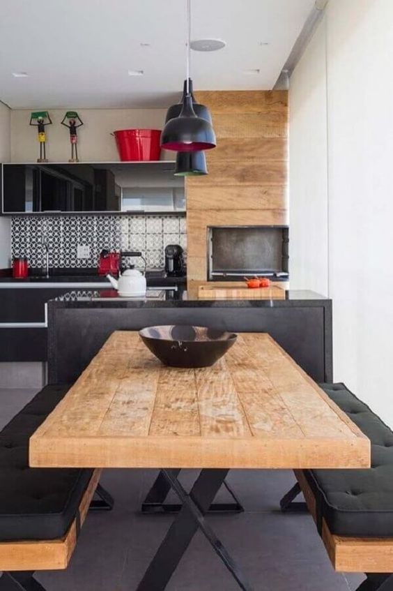 Cuisine intégrée avec table à manger et bancs en bois avec intérieur noir. 