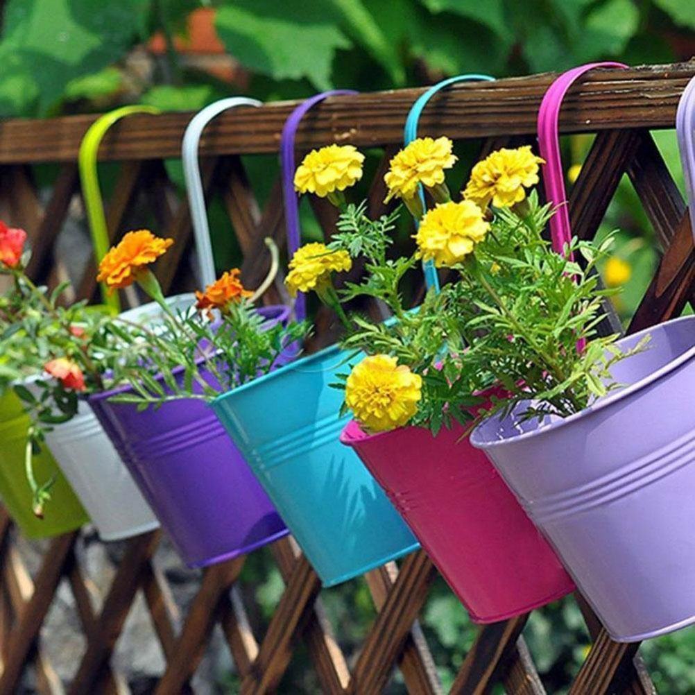 Pour égayer le jardin, placez des fleurs dans des seaux en métal colorés.