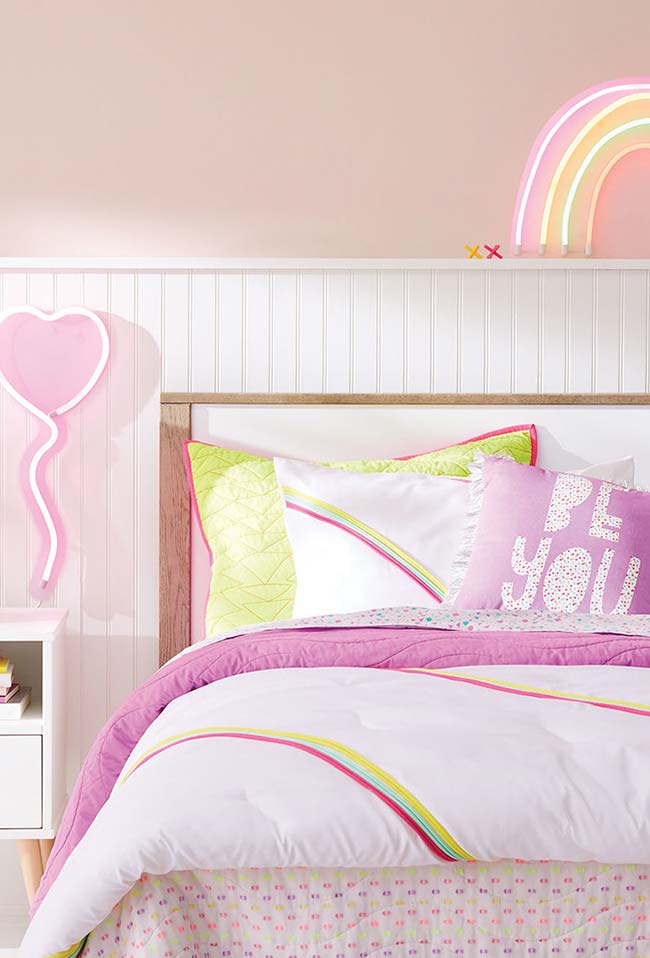 Chambre de jeune fille avec un arc-en-ciel au néon sur le lit