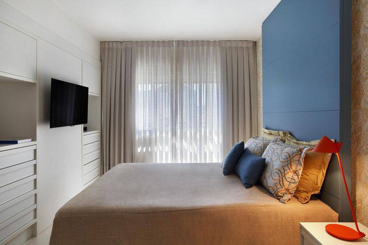 Chambre double prévue avec tête de lit en bois et finition bleue.