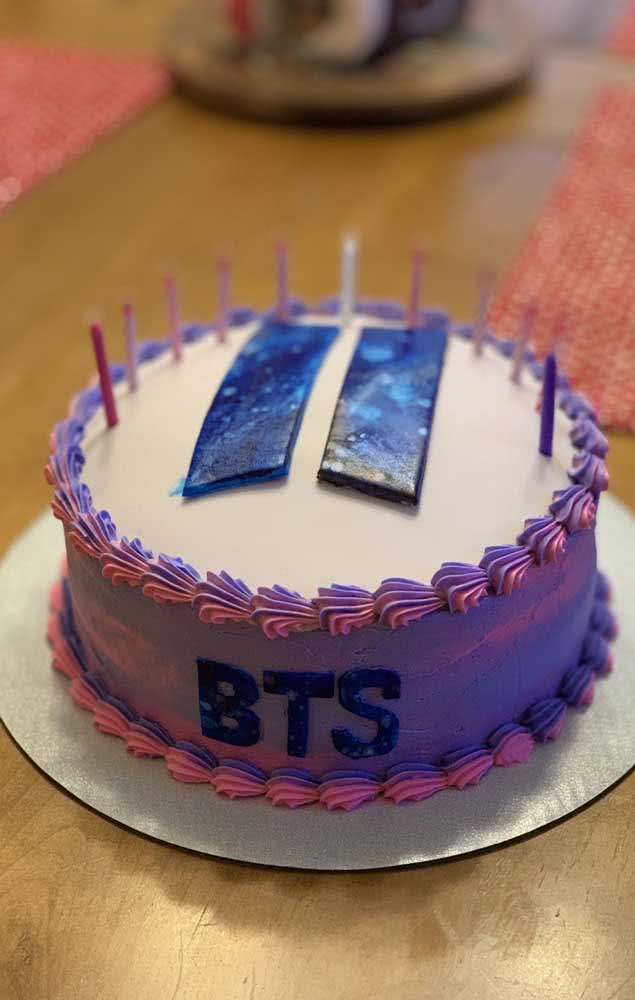 Un gâteau BTS minimaliste rond décoré uniquement de chantilly et du logo du groupe