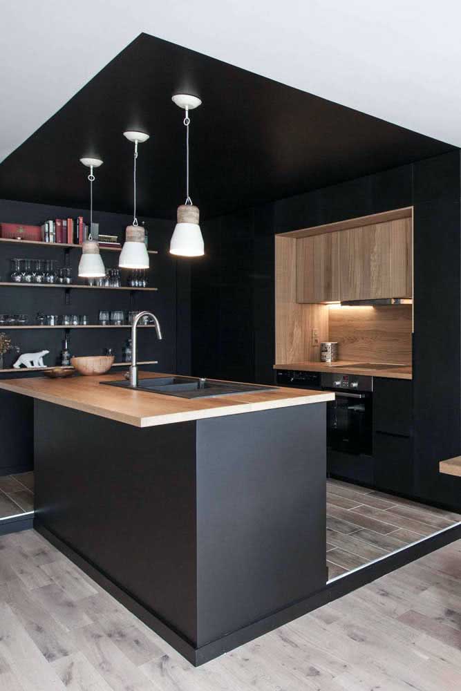 Une cuisine en forme de U entourée de peinture noire sépare l'environnement du reste de la maison