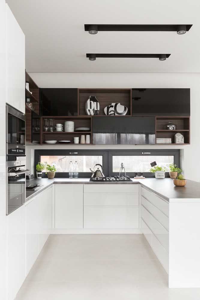 La cuisine blanche en forme de U contraste avec les étagères en bois foncé